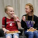 Sporting opposing team gear, Lauren Rice and Avery Kirkman, right, enjoy chatting together as Dutch Hill Elementary held an Apple Cup-themed Dads and Donuts event, with the gym decked out in Cougar and Husky colors, on Wednesday, Nov. 21, 2018 in Snohomish, Wa. (Andy Bronson / The Herald)