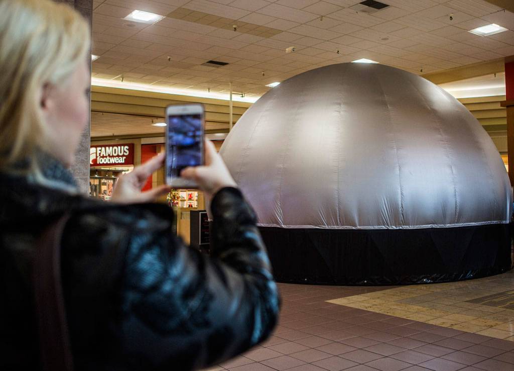 A woman stops to take a picture of the Planetarium 360 at before going inside for a show at the Everett Mall on Saturday. (Olivia Vanni / The Herald)