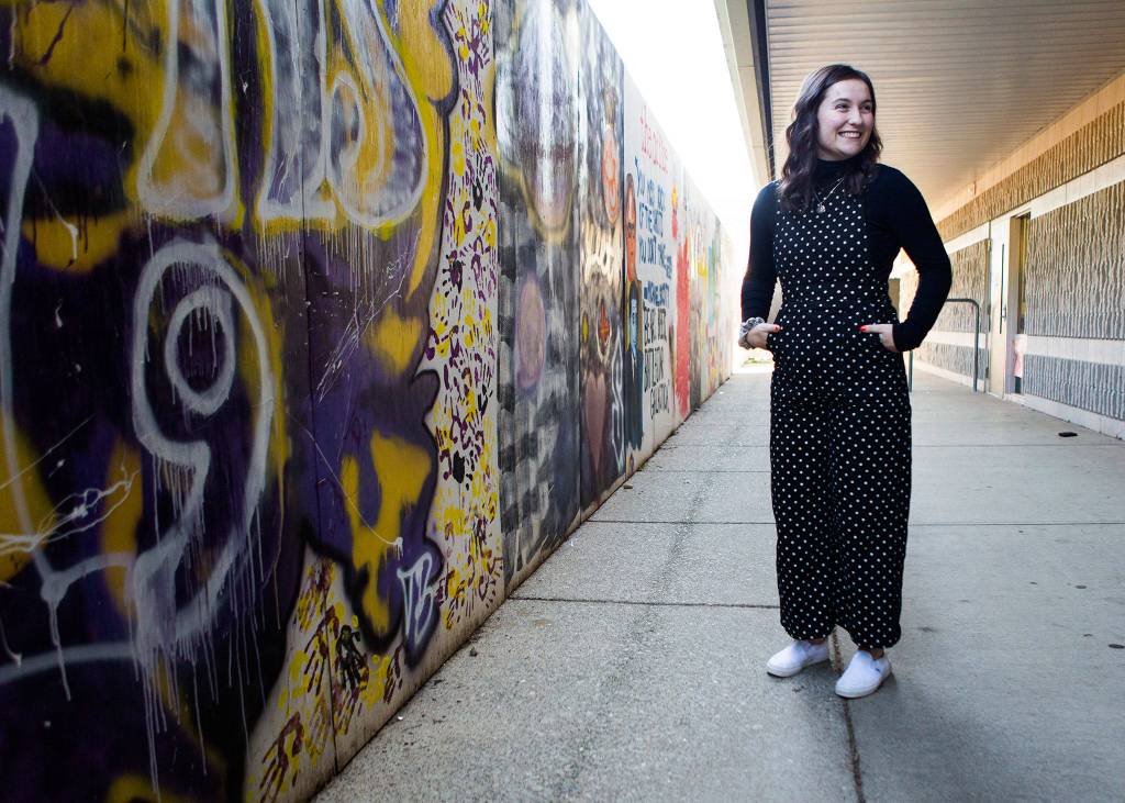 Lexus Thomas, 17, stands in front of <a href="https://www.heraldnet.com/news/she-turned-lake-stevens-high-schools-remodel-into-art/" target="_blank">the project she spearheaded</a>  a large construction wall decorated with multiple murals  on Nov. 8 in Lake Stevens. (Olivia Vanni / The Herald)