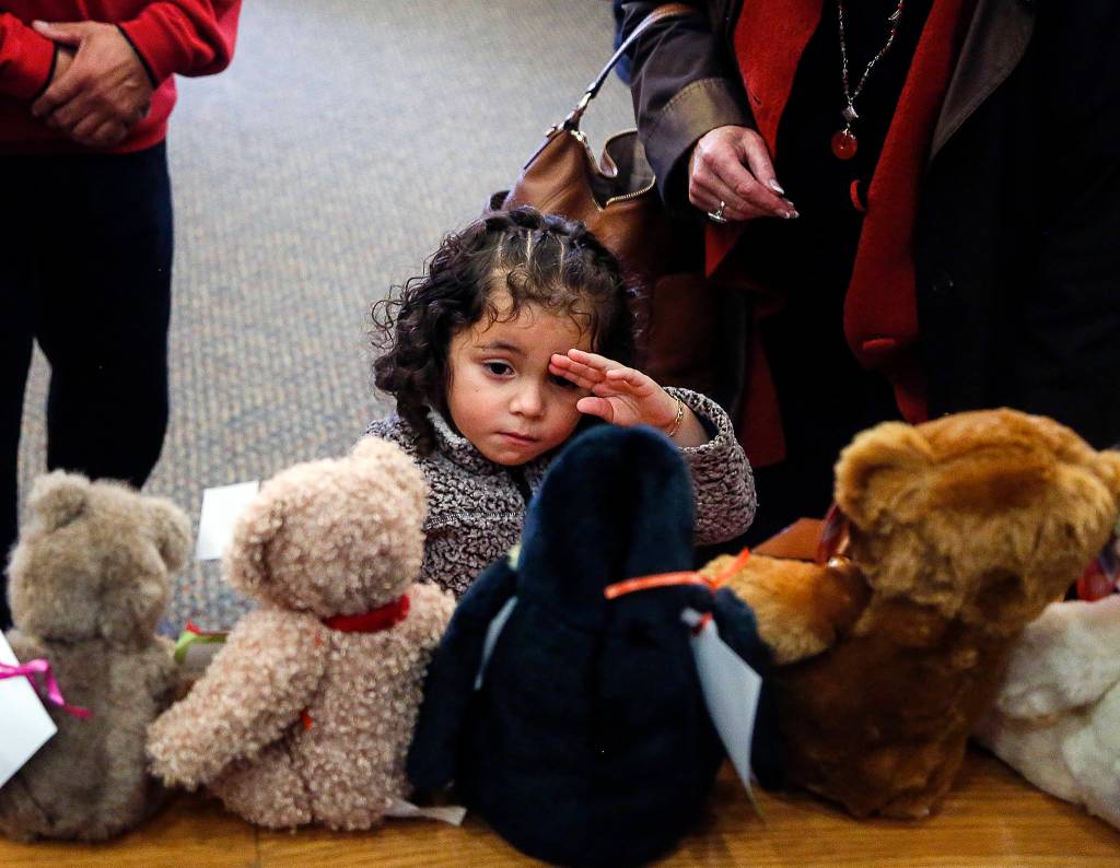 As her adoptive parents and others watch, Fernanda Yaresli Gonzales-Martinez tries to pick out a stuffed animal from a variety of them lined up on the rail of the jury box in Judge David Kurtzs courtroom, following her adoption proceedings at <a href="https://www.heraldnet.com/news/families-created-with-stroke-of-a-pen-and-strike-of-a-gavel/" target="_blank">Snohomish County Superior Courts National Adoption Day</a>. (Dan Bates / The Herald)