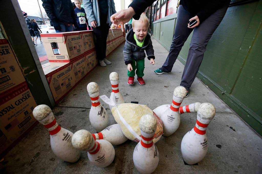 Liam Mourning, 6, gets a hand at Turkey bowling from his mother Shelly outside Grocery Outlet at the <a href="https://www.heraldnet.com/news/hundreds-run-through-arlington-before-thanksgiving-dinner/" target="_blank">Turkey Trot 5K</a> on Nov. 22 in Arlington. (Andy Bronson / The Herald)
