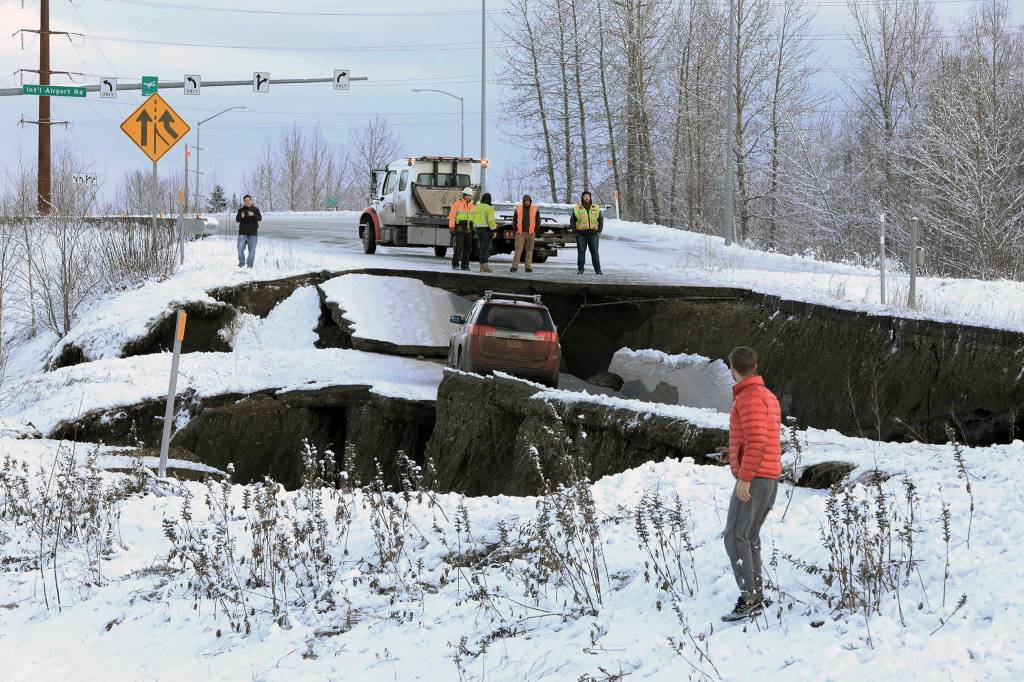 Highway workers and spectators look at a car stuck on a section of an off-ramp that collapsed during an earthquake Friday morning in Anchorage, Alaska. The driver was not injured attempting to exit Minnesota Drive at International Airport Road. (AP Photo/Dan Joling)