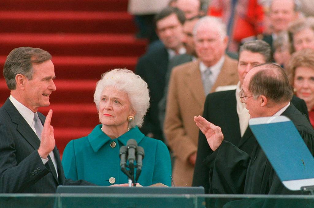 President George H.W. Bush raises his right hand as he is sworn into office on Jan. 20, 1989, as the 41st president of the United States by Chief Justice William Rehnquist outside the west front of the Capitol as first lady Barbara Bush holds the bible for her husband. (Bob Daugherty / AP file)