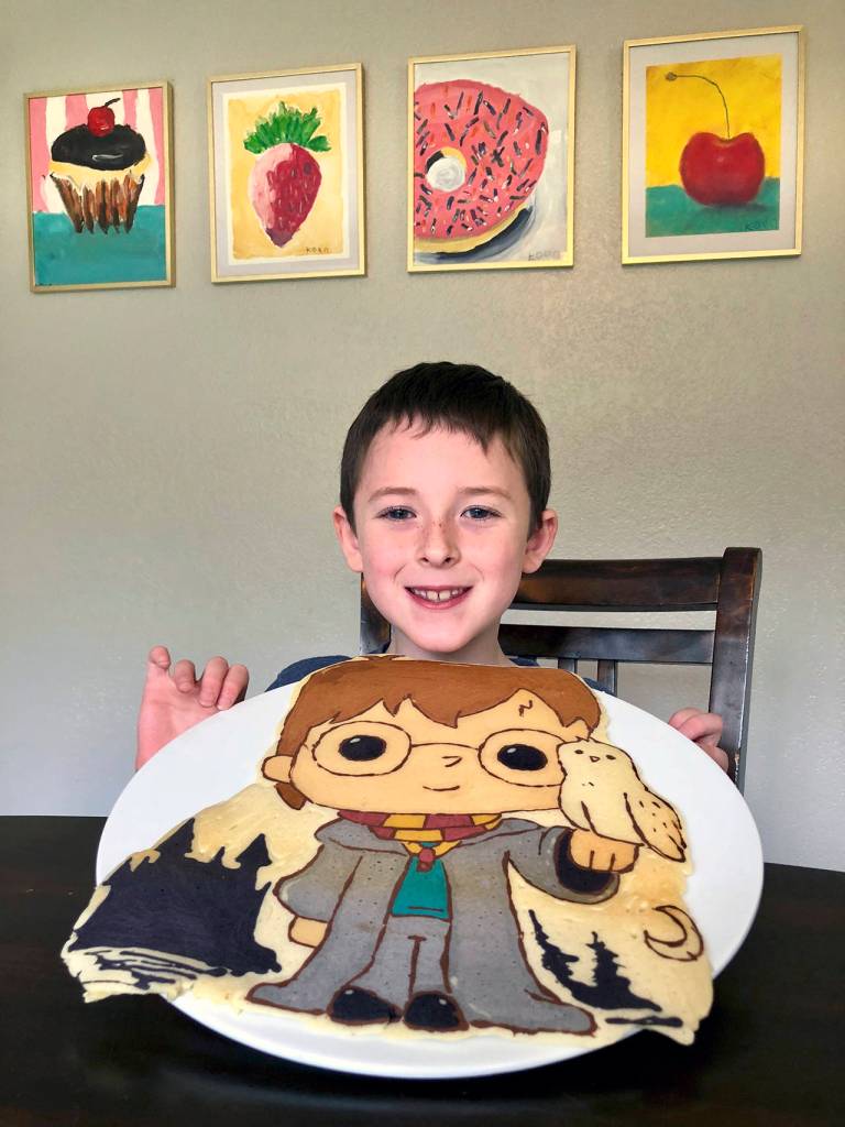 Koen Nebel, 7, holds a Harry Potter pancake he helped his father make  and later helped eat. The artwork on the wall was done by Koen. (Andrea Brown / The Herald)