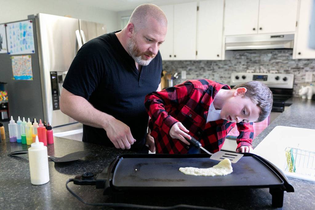 Pancake artist Brek Nebel (left) and his son Koen, 7, create work to create a rainbow in their Snohomish kitchen. (Kevin Clark / The Herald)