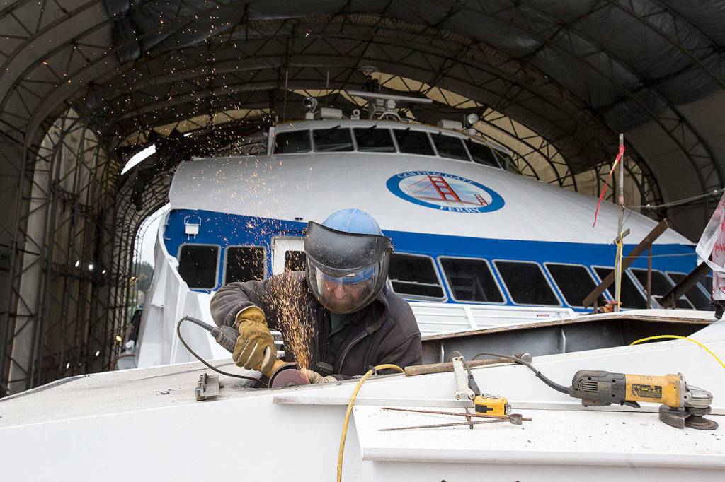 Sparks fly as shipfitter Duane Hunt grinds and cuts to widen an opening for a ships stack at Nichols Brothers Boat Builders. Behind him is a ship bound for the San Francisco ferry system. (Andy Bronson / The Herald)