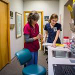 Susan Sanderson (left) and Clarisa Shook look to see what patient is next at the Safe Harbor Clinic in Stanwood. (Olivia Vanni / The Herald)