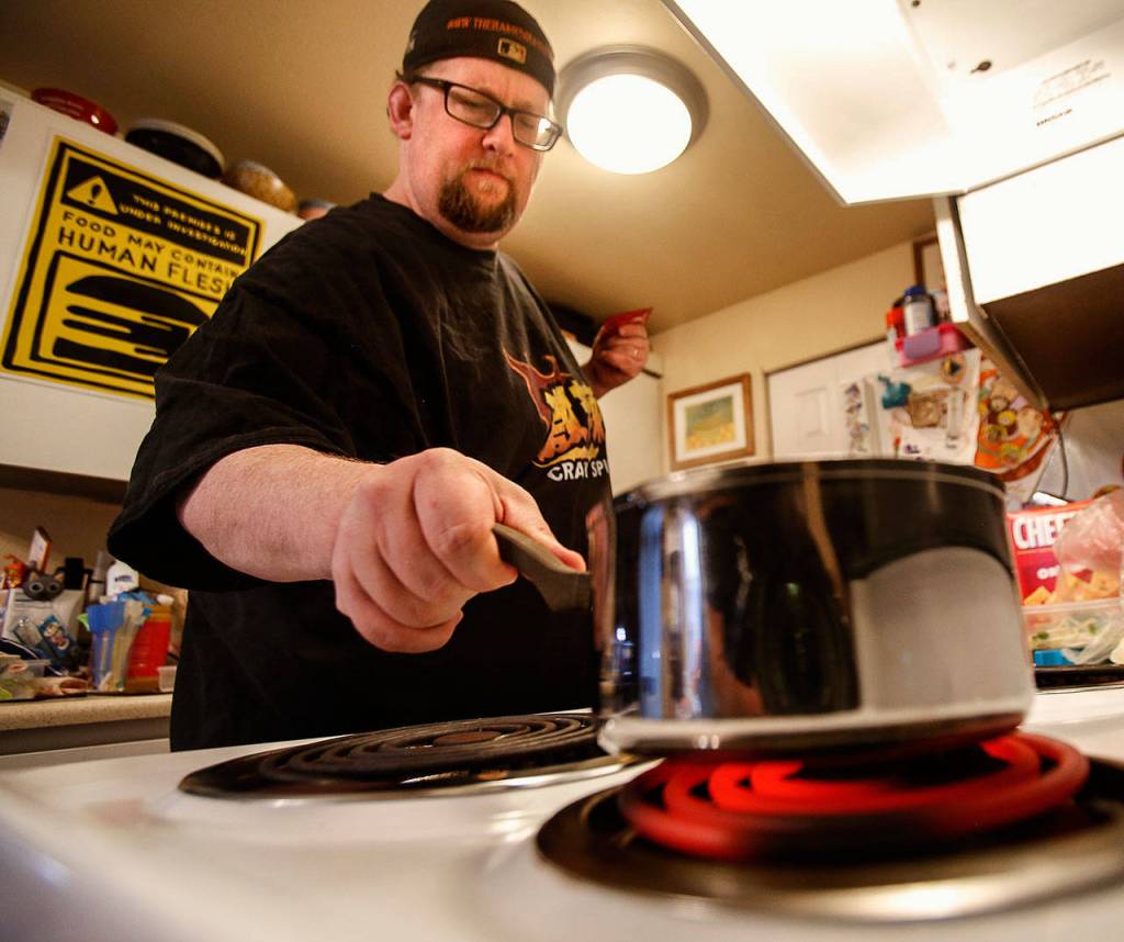 Hans Lienesch gets a pot of ramen going on the kitchen stove. (Dan Bates / The Herald)