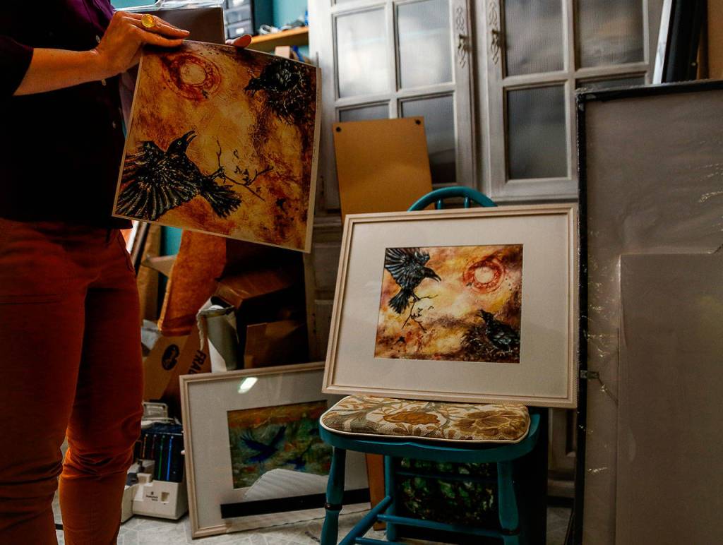In her studio, Susan Ringstad Emery talks about some of her favorite things, which include ravens. Concentric circles, such as the red ones on the paintings, are a common theme in Native Alaskan art, she said. (Dan Bates / The Herald)