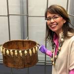 Everett artist Susan Ringstad Emery with an artifact from the Smithsonian collection at the Anchorage Museum. Items are tethered to movable metal racks to protect them from earthquake damage.