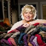 Snohomish artist Jackie Cort holds handmade hats for her annual sock-hat-scarf collection for two social service agencies in Everett. Cort, who gets hundreds of items every year from artists and friends, is having a donation drop-off night Friday that is open to the community. (Andy Bronson / The Herald)
