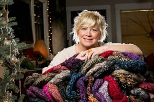 Snohomish artist Jackie Cort holds handmade hats for her annual sock-hat-scarf collection for two social service agencies in Everett. Cort, who gets hundreds of items every year from artists and friends, is having a donation drop-off night Friday that is open to the community. (Andy Bronson / The Herald)
