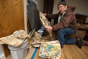 Keith Moser holds one of the many old newspaper found in the walls to insulate his home after construction crews tore down drywall in his Everett home. (Andy Bronson / The Herald)