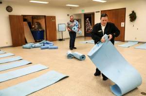 Andrea Reedy, (right) a Salvation Army pastor, and volunter Rick Barber arrange mats at Everetts cold weather shelter located at the Salvation Army. Monday night was the first night the site was open this season. (Lizz Giordano / The Herald)