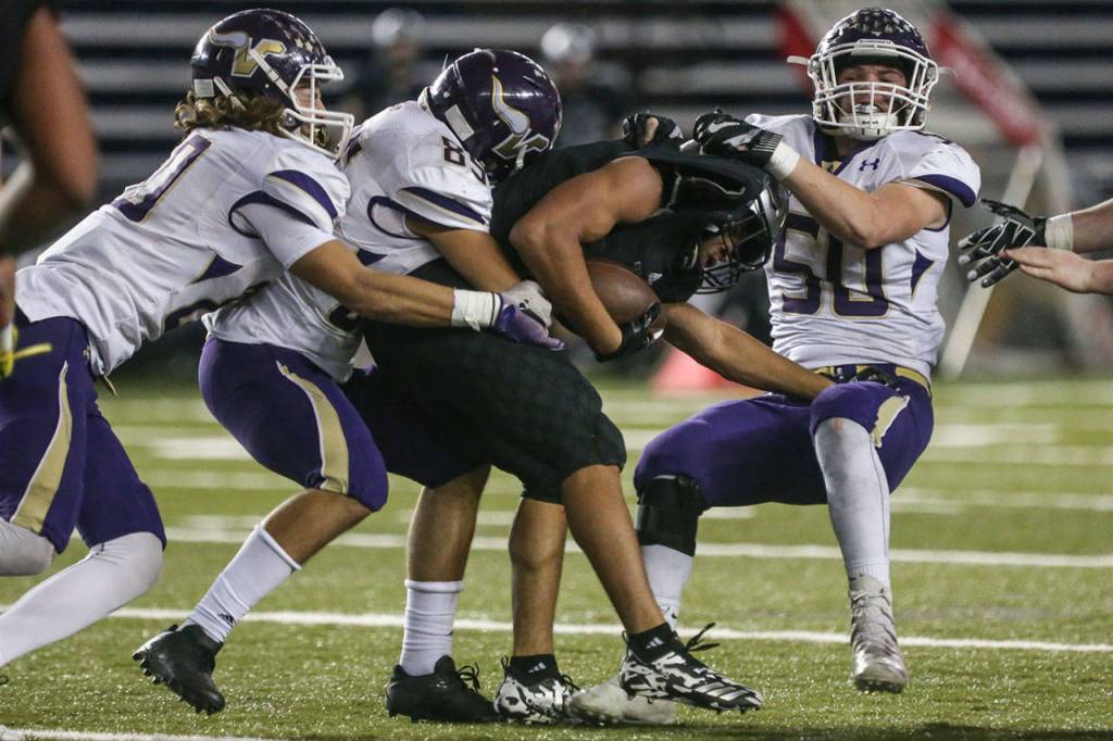 Unions Isaiah Jones is tackled by a host of Lake Stevens defenders during the 4A state football championship game on Dec. 1, 2018, at the Tacoma Dome. (Kevin Clark / The Herald)