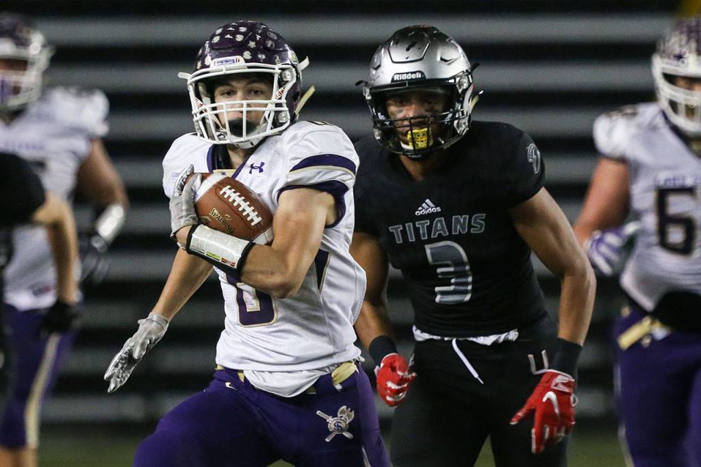 Lake Stevens Dallas Landeros runs the ball with Unions Darien Chase trailing during the 4A state football championship game on Dec. 1, 2018, at the Tacoma Dome. (Kevin Clark / The Herald)