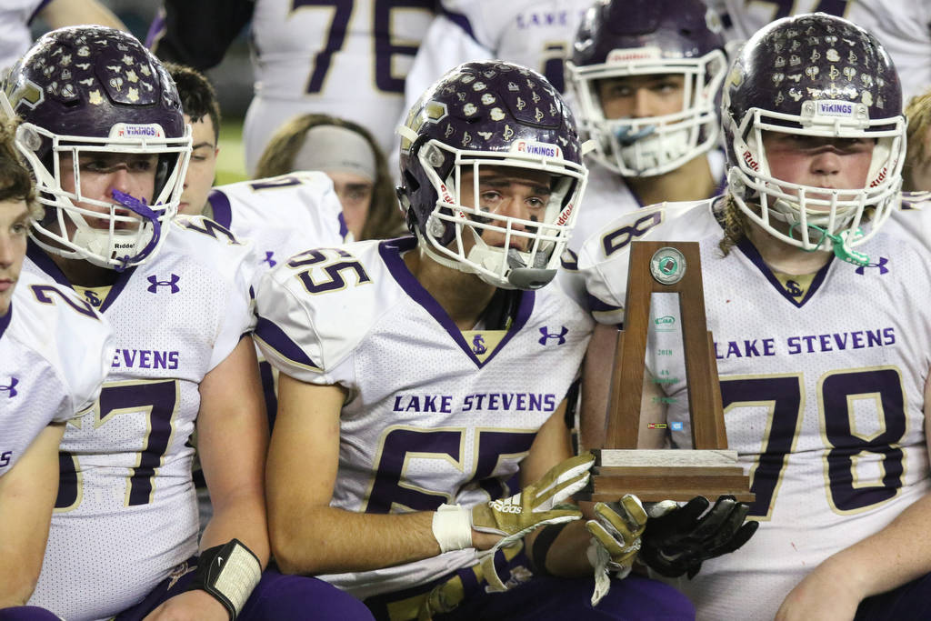 Lake Stevens Jager Hill holds the second-place trophy with teammates afterthe Vikings lost to Union 52-20 in the 4A state football championship game on Dec. 1, 2018, at the Tacoma Dome. (Andy Bronson / The Herald via AP)