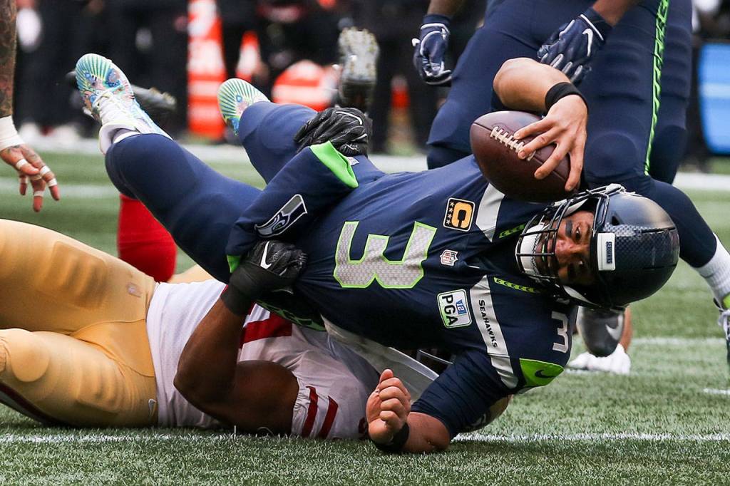 Seahawks quarterback Russell Wilson is tackled by 48ers Malcolm Smith Sunday afternoon at CenturyLink Field in Seattle on December 2, 2018. Seahawks won 46-16. (Kevin Clark / The Herald)