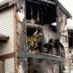 A firefighter works on a burned apartment above the unit where 3-year-old twin girls were rescued by two Everett Firefighters who crawled on the floor through thick smoke, heat and flames to save their lives. (Andy Bronson / Herald file)