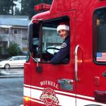 Firefighter Tyler Griffith sits in the drivers seat wearing a Santa cap. Local firefighters will be decorating a fire engine this year as they drive around gathering donations and meeting with residents. (City of Bothell)