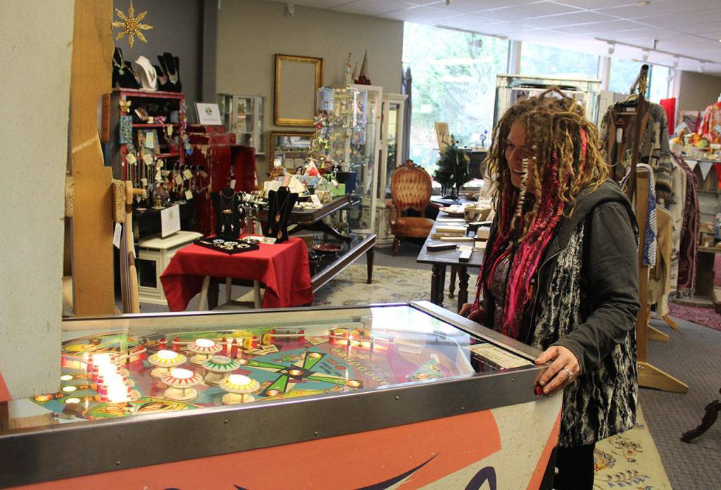 Carie Elder, owner of Whidbey Wonders in Clinton, takes a break to play the vintage pinball machine at her new store. The game is there for those not so much into shopping, she says. (Patricia Guthrie / South Whidbey Record)