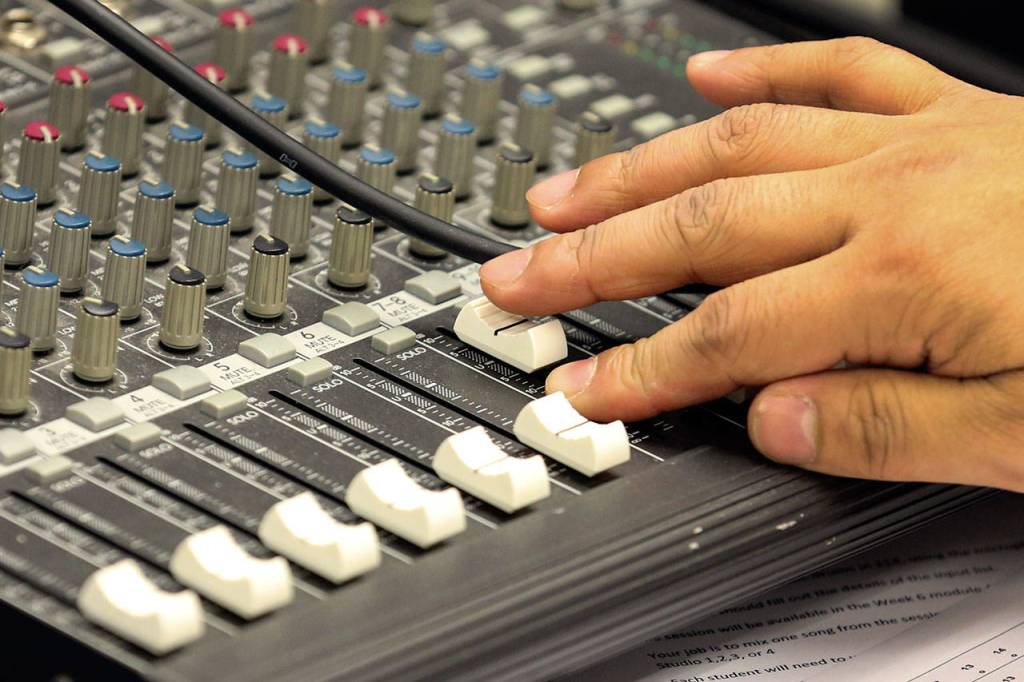 An audio engineering student adjusts sound levels while the orchestra plays. (Kevin Clark / The Herald)