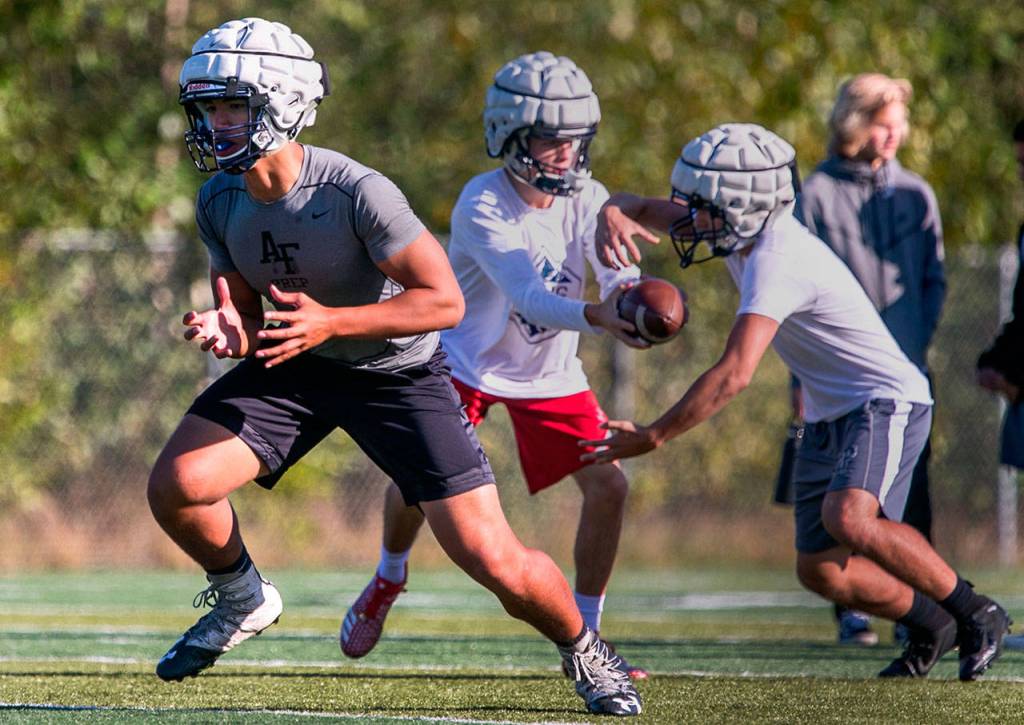 Maake Fifita (left) blocks with Ayden Ziomas handing off to Corbin Ferrie Thursday afternoon during practice Oct. 4, at Glacier Peak High School in Snohomish. (Kevin Clark / The Herald)