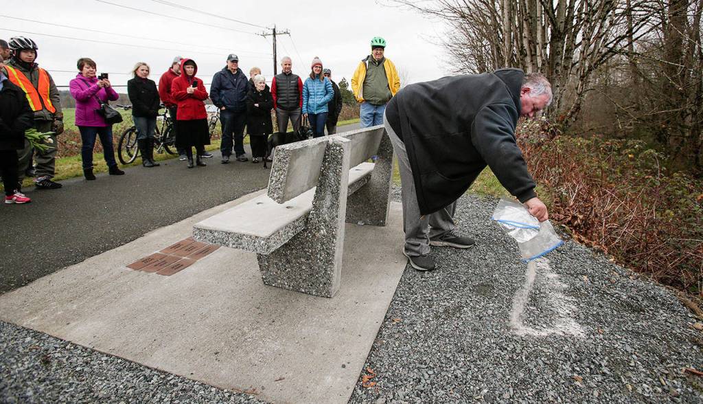 Friends, family and members of the The Big Shots Bicycle Group watch Jeff ODonnell spread his fathers ashes behind a bench in Dan ODonnells name along the Centennial Trail on Wednesday, Dec. 19, in Arlington. (Andy Bronson / The Herald)