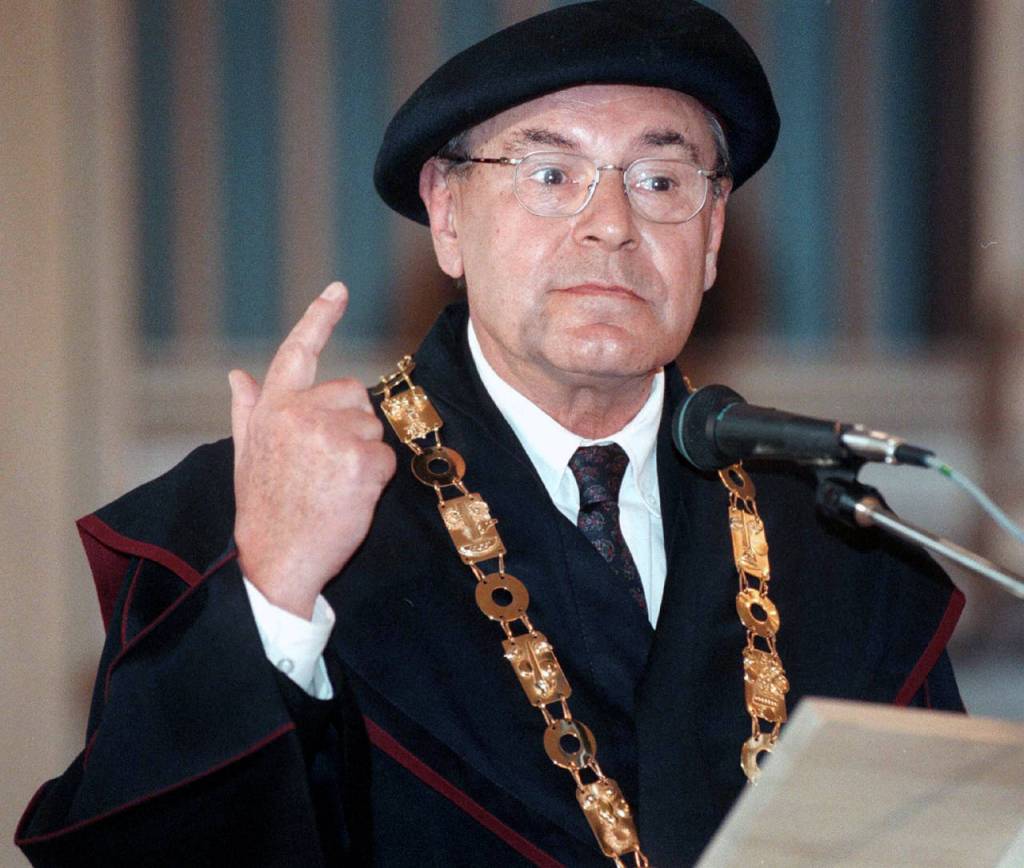 Wearing ceremonial dress and golden chain over his neck, Oscar-winning film director Milos Forman makes a point as he delivers an address after he was presented the honorary doctors degree of the Czech Academy of Performing Arts (AMU) for his lifetime achievements in Prague on Jan. 16, 1998. (AP Photo/Stanislav Zbynek/CTK, file)