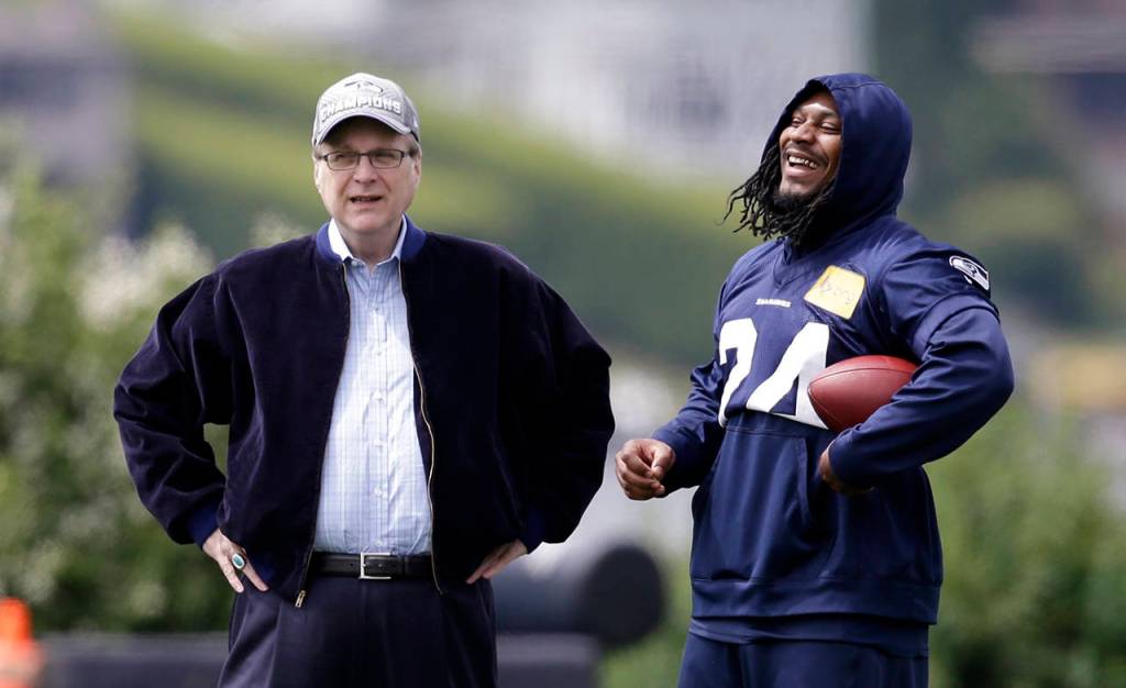 In this June 18, 2018 photo, Seattle Seahawks owner Paul Allen (left) talks with running back Marshawn Lynch on the sidelines at an NFL football minicamp practice in Renton. Paul G. Allen, who co-founded Microsoft with his childhood friend Bill Gates before becoming a billionaire philanthropist, technology investor and owner of the Seattle Seahawks, died Oct. 15. (AP Photo/Elaine Thompson, File)
