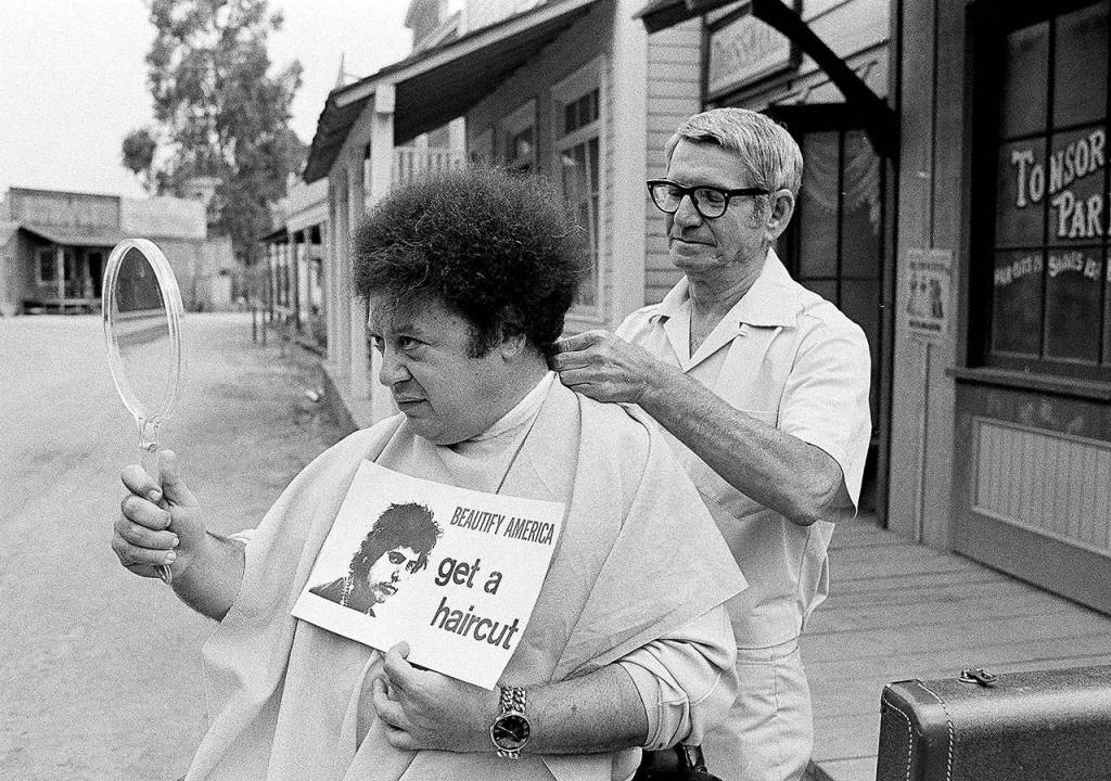 In this Aug. 15, 1968 photo, comedian Marty Allen, fuzzy-haired member of the comedy team of Allen & Rossi, has his hair styled by barber Sol Goldstein in Hollywood, California. Allen died Feb. 12, 2018, of complications from pneumonia. He was 95. (AP Photo/Wally Fong, File)