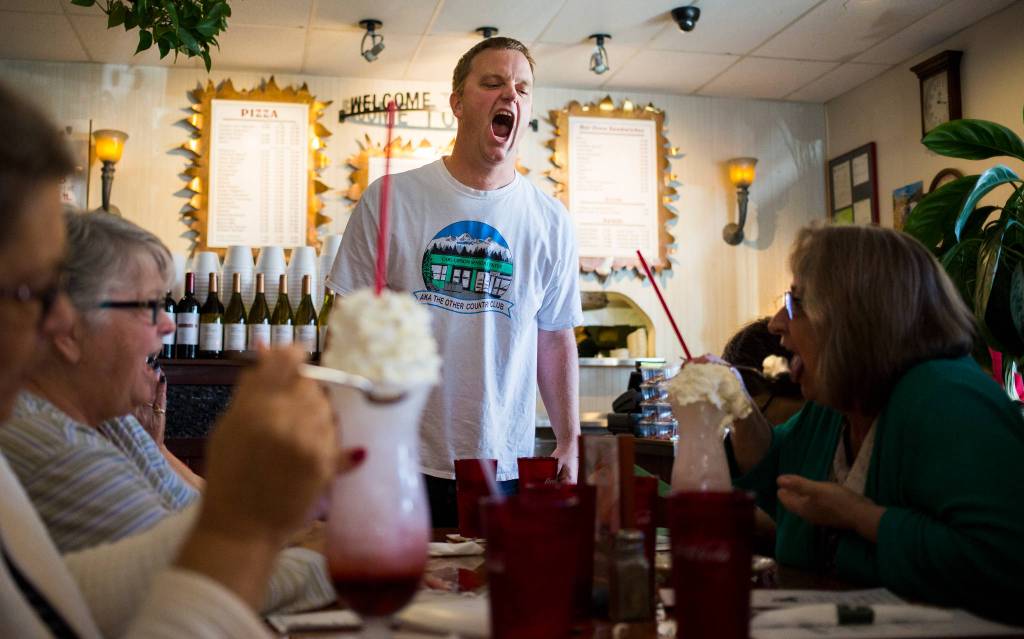 Program Coordinator Eric Wollan dares Paula Darrow, right, to eat the whipped cream off her Italian soda like a shark during a group trip from the Everett Senior Center to Contos Pizza & Pasta on Monday, Sept. 17, in Lake Stevens. (Andy Bronson / The Herald)
