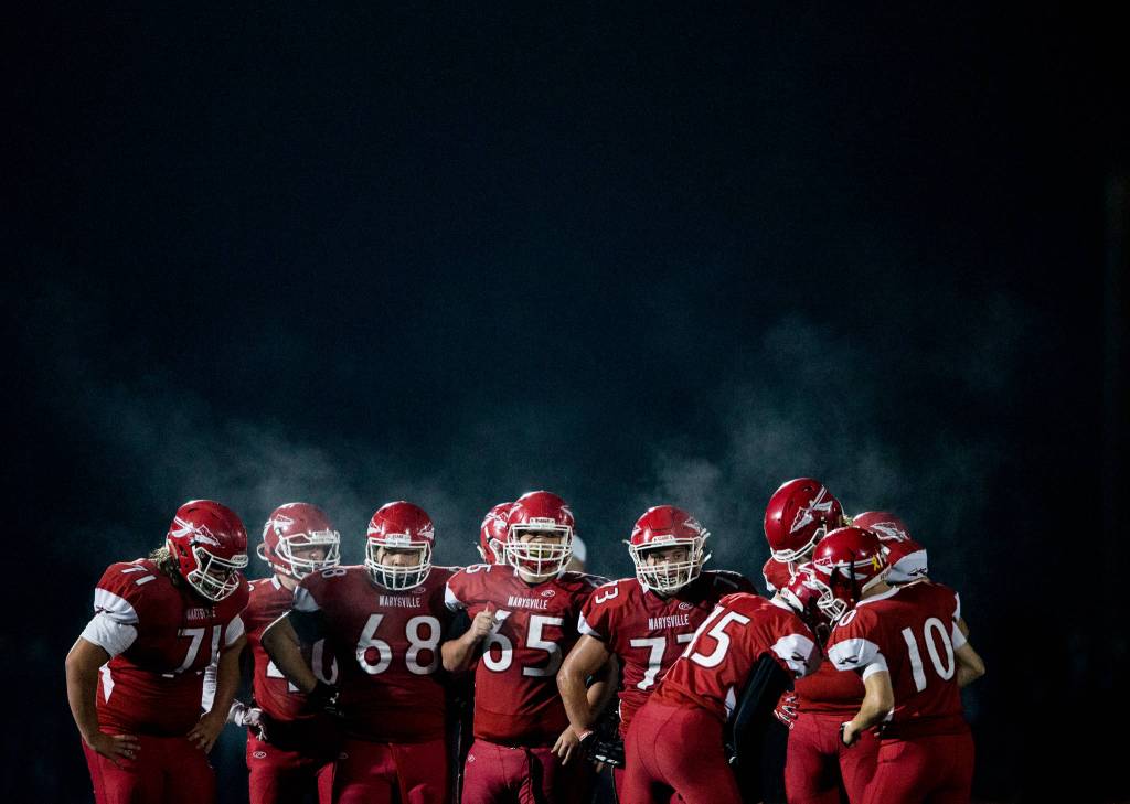 The Marysville-Pilchuck offense huddles before the snap during the game on Oct. 5, in Marysville. (Olivia Vanni / The Herald)