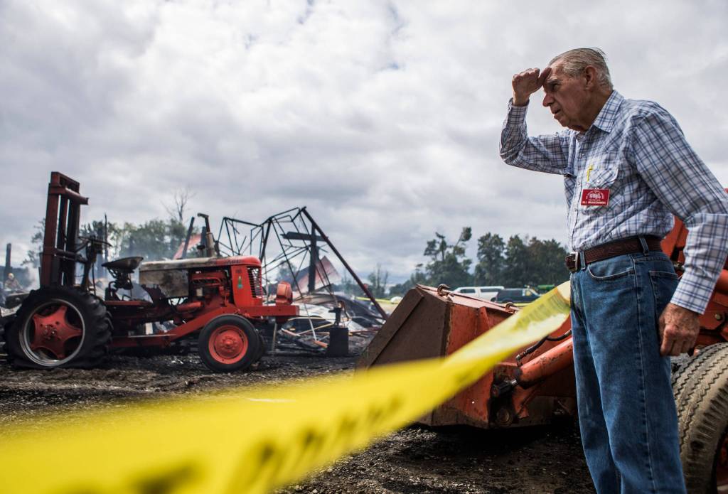 Bill Wojciechowski, a member of the Sky Valley Stock & Antique Tractor Club, looks out over the rubble of the barn that caught fire early Saturday morning at the Sky Valley Stock and Antique Tractor Show grounds on Saturday, Aug. 11, in Monroe. (Olivia Vanni / The Herald)