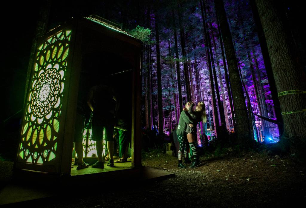 Two friends hug each other as they explore the Axis Mundi art installation at the Summer Meltdown on Thursday, Aug. 2, in Darrington. (Olivia Vanni / The Herald)