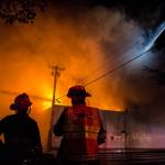 Everett Fire Department firefighters watch as water is sprayed on the Judd & Black appliance store at 3001 Hewitt Ave on Sept. 21, in Everett. (Olivia Vanni / The Herald)