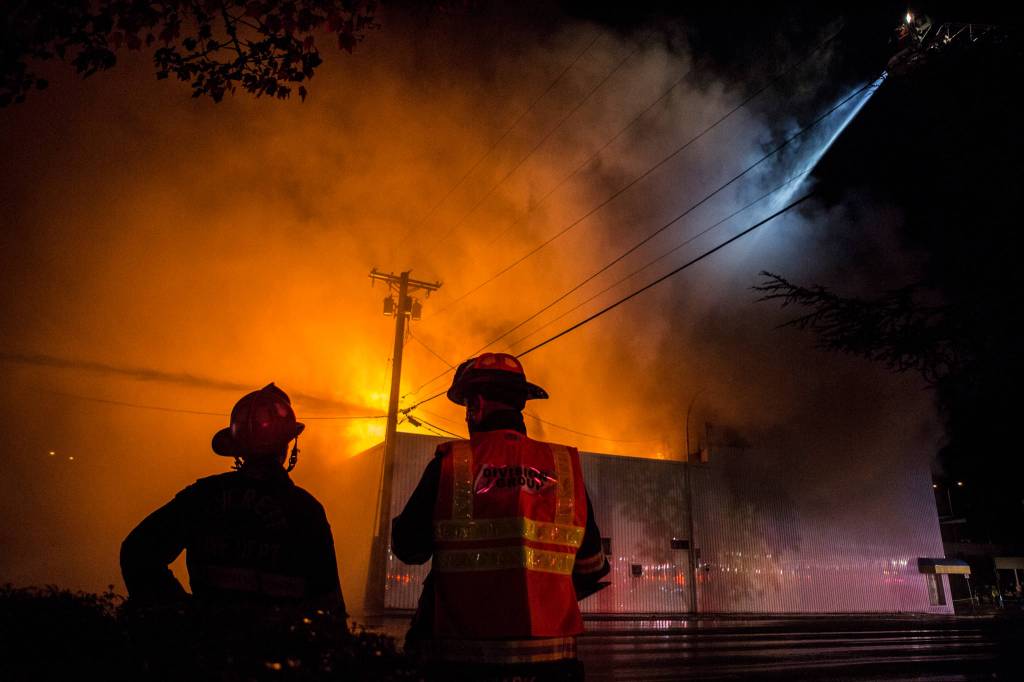 Everett Fire Department firefighters watch as water is sprayed on the Judd & Black appliance store at 3001 Hewitt Ave on Sept. 21, in Everett. (Olivia Vanni / The Herald)
