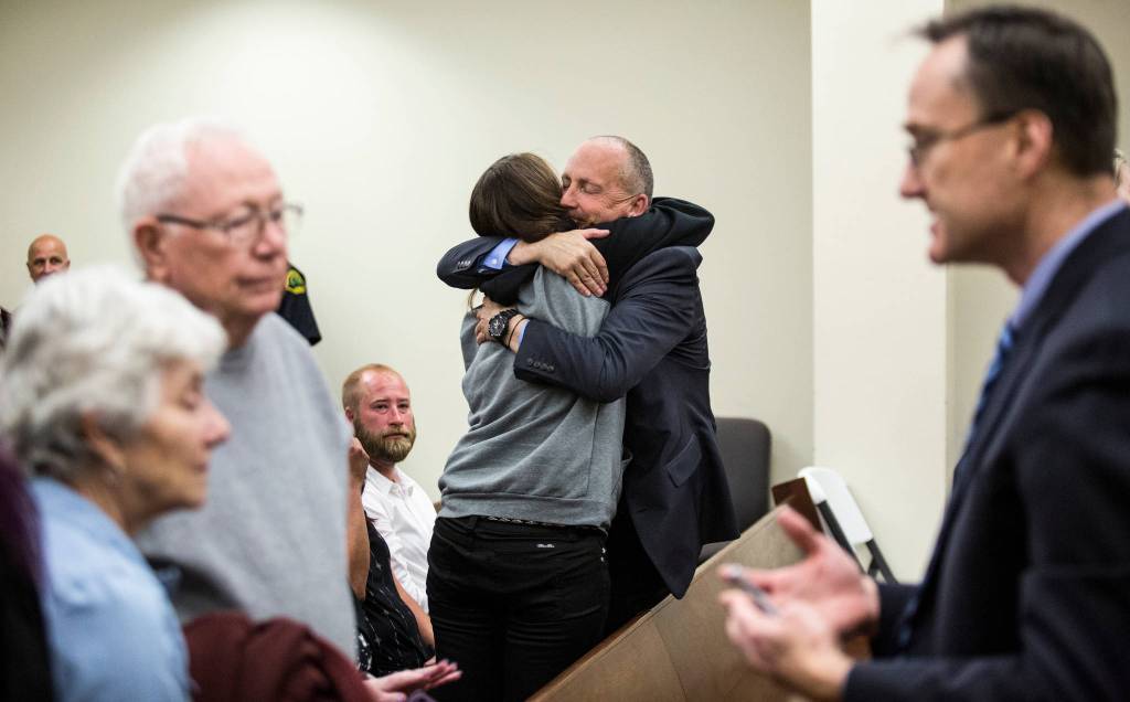 Snohomish County Detective Dave Fontenot is hugged by friends and family of Monique Patenaude as Snohomish County chief criminal deputy prosecutor Craig Matheson talks with parents of Patrick Shunn after the quilty verdicts in the trial of John Reed at the Snohomish County Courthouse on Wednesday, May 30, in Everett. Reed was convicted in the murders of Monique Patenaude and Patrick Shunn. (Andy Bronson / The Herald)