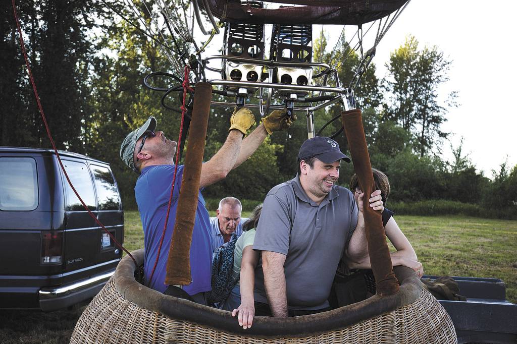 As pilot Jay Woodward fire hot air into the balloon, Mark VanAntwerp winces at the heat and noise it makes during liftoff of a hot air balloon on Monday, June 18, 2018 in Snohomish, Wa. Licensed by the Federal Aviation Administration, Woodward has been piloting hot air balloons for 20 years. (Andy Bronson / The Herald)