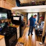 Michael Miller rubs the head of his cat, Underfoot, inside his tiny home at the Lakeside RV Park. The 245-square-foot house was built around his need for a full-sized kitchen. (Andy Bronson / The Herald)