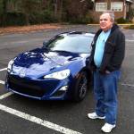 In this 2013 photo, Alan Naiman poses with his new car, an unusual extravagance for him, in Seattle. (Shashi Karan via AP)