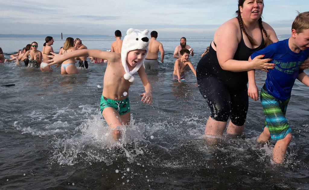 Sporting a polar bear hat, Nolan OCain, 6, retreats back to the warm beach after diving in Tuesday, Jan. 1, during the annual Polar Bear Plunge at Bracketts Landing in Edmonds. (Andy Bronson / The Herald)