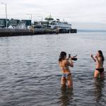 After missing the first wave, Hope Juzon, left, and Catherine Do take photos as they hit the Puget Sound waters Tuesday, Jan. 1, during the annual Polar Bear Plunge at Bracketts Landing in Edmonds. (Andy Bronson / The Herald)