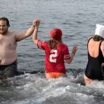 Participants going and and coming out of the water high five each other Tuesday, Jan. 1, during the annual Polar Bear Plunge at Bracketts Landing in Edmonds. (Andy Bronson / The Herald)