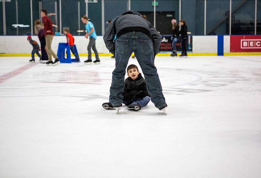 Gavin Bell, 8, looks up at his dad during the community skate after slipping at the XFINITY Community Ice Rink on Dec. 28 in Everett. (Olivia Vanni / The Herald)