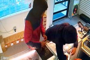 Two teenagers are seen on camera reaching behind a display case and taking handguns Sunday at a Lynnwood store. (Lynnwood Police Department)