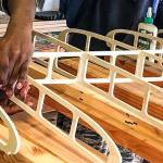 Taking instruction from Calvin Nichols, court-involved kids with Snohomish County Juvenile Courts Youth Enrichment Services glue intricate parts of the custom paddleboards frame together. (Contributed Photo)