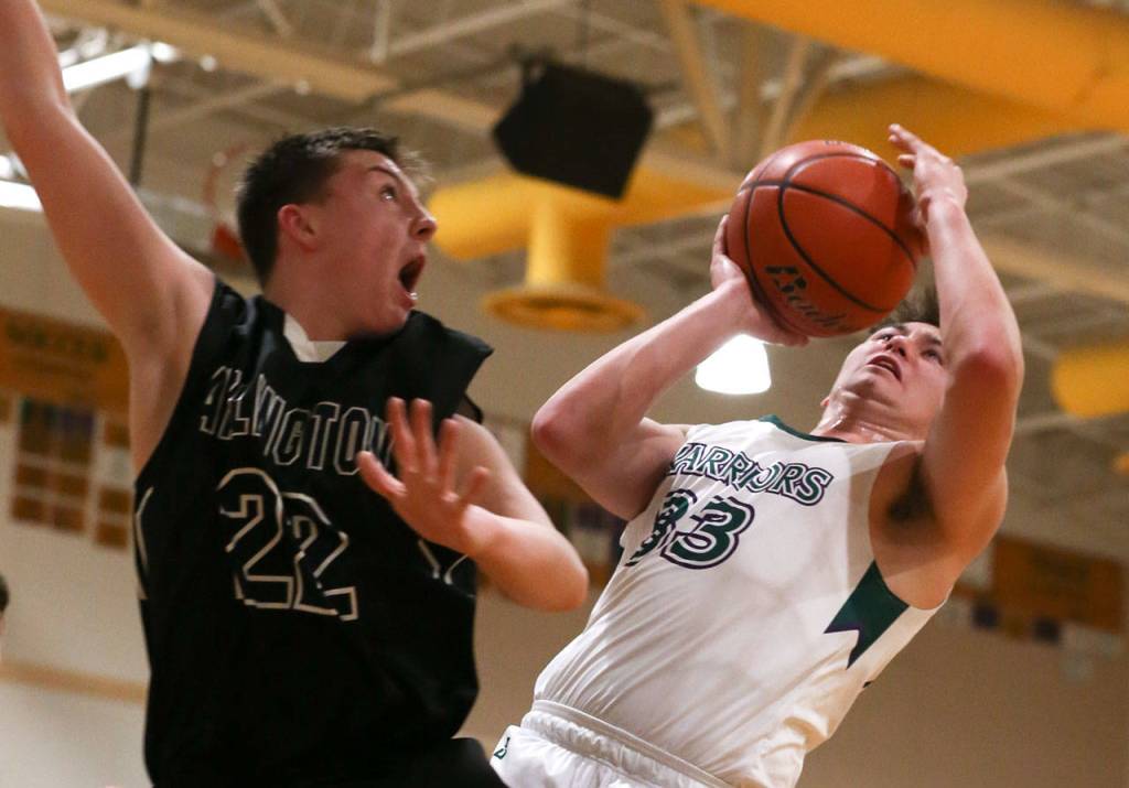 Edmonds-Woodways Tai Starchman (right) attempts a shot over Arlingtons Ethan Martin at during a Wesco 3A boys basketball game Wednesday in Edmonds. Starchman and the Warriors won 74-71. (Kevin Clark / The Herald)