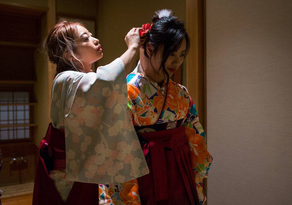 Shoka Ludden, left, helps Reika Nemoto, right, re-pin part of her headpiece before the Coming of Age ceremony at Everett Community College. (Olivia Vanni / The Herald)