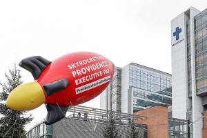 Employees with Providence Hospice and Homecare of Snohomish County raised a 24-foot inflatable rocket outside Providence Regional Medical Center Everett on Jan. 10. They wanted to draw attention to the high salaries many executives receive. (Lizz Giordano / The Herald)